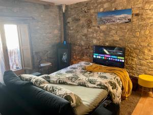 uma cama num quarto com uma parede de pedra em Tavertet un poble preciós em Tavertet