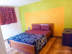 Cama pequeña en habitación con paredes verdes y amarillas en Mansa Home Stay en Nainital
