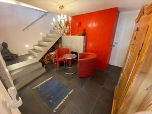 Cette chambre est dotée d'un escalier avec des murs rouges et des chaises rouges. dans l'établissement Single Haus auf mehreren Ebenen - herzlich willkommen in der lichtdurchfluteten Casa Carina, à Dongio