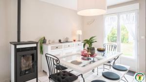 a white kitchen with a table and a fireplace at Gite Les Azalées 8 personnes 10mn de Compiègne in Le Meux