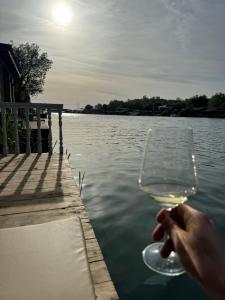 a person holding a glass of wine near the water at Pearl Cottage Ada Bojana in Ulcinj