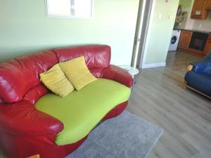 Un sofá de cuero rojo con dos almohadas amarillas. en Atlantic Point Stunning Sea View, en Bundoran