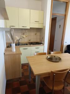 una cucina con armadi bianchi e tavolo in legno di Appartamento Levante vistamare a Caorle