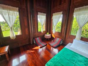 a bedroom with a bed and two chairs and windows at The Thai House Homestay & Thai Cooking Experiences in Ban Bang Sano +60 photos