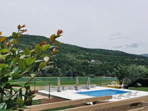 une piscine avec des chaises et des parasols et une montagne dans l'établissement Hotel Noor Konjic, à Konjic