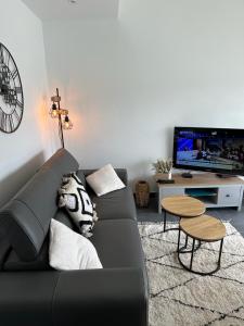 un sofá negro en una sala de estar con TV en Jetez l'ancre à la marina de deauville, en Deauville