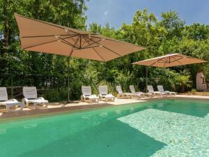 einen Pool mit Sonnenschirmen und Stühlen sowie einen Pool in der Unterkunft Spacious farmhouse with private heated pool in a rustic garden in Nantheuil