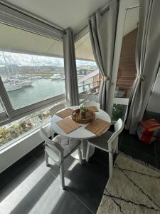 uma mesa e cadeiras num quarto com uma grande janela em Jetez l'ancre à la marina de deauville em Deauville