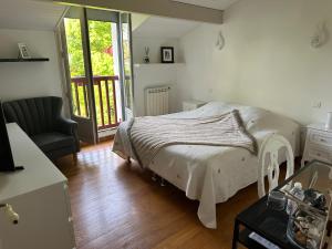 ein Schlafzimmer mit einem Bett, einem Stuhl und einem Fenster in der Unterkunft LES CHAMBRES D'ARRAUNTZ in Ustaritz