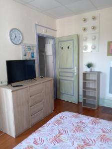 a room with a tv on a dresser and a clock at Studio Continental côté jardin in Vittel