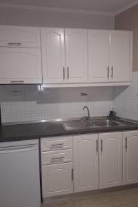 a kitchen with white cabinets and a sink at villa verleti in Parga