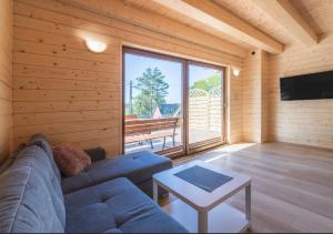 ein Wohnzimmer mit einem blauen Sofa und einem großen Fenster in der Unterkunft Karmelowe Domki Kaszuby, 80m do jeziora in Stężyca