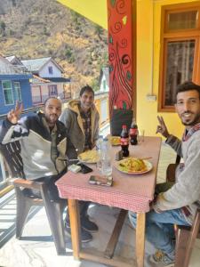 um grupo de três homens sentados à mesa em SURAJ GUEST HOUSE TOSH em Tosh