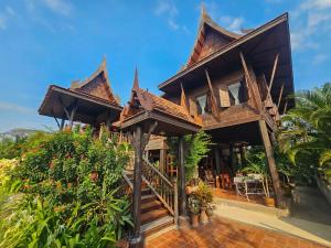 ein Haus mit einem Holzdach in der Unterkunft The Thai House Homestay & Thai Cooking Experiences in Ban Bang Sano