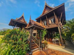a house with a wooden roof at The Thai House Homestay & Thai Cooking Experiences in Ban Bang Sano