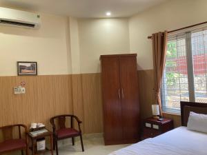 een slaapkamer met een bed, een kast en een raam bij Maily Hostel in Hue