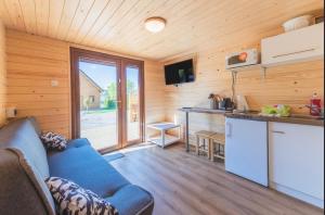 ein Wohnzimmer mit einem blauen Sofa und einer Küche in der Unterkunft Karmelowe Domki Kaszuby, 80m do jeziora in Stężyca