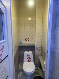 a bathroom with a toilet with two signs on the wall at Happy House in Chişinău +1 photo
