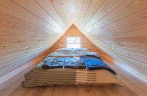 ein Bett in einem winzigen Haus mit Fenster in der Unterkunft Karmelowe Domki Kaszuby, 80m do jeziora in Stężyca