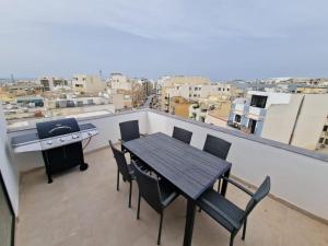 a table and chairs on a balcony with a grill at Sky Apartment 3 in St Paul's Bay