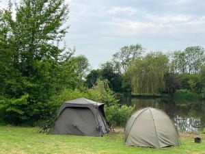 a tent sitting in the grass next to a lake at Amber Lodge Hickstead-B in Burgess Hill