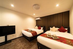 a hotel room with two beds and a flat screen tv at 84-5, Shiomi 301, Entire room for rent in Tokyo