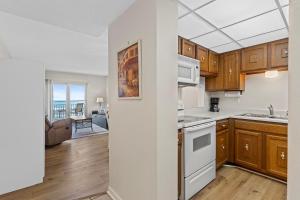 a kitchen with wooden cabinets and white appliances at Sea Coast Gardens II 316 in New Smyrna Beach