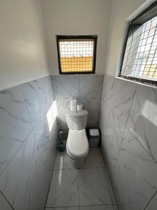 a bathroom with a white toilet and a window at Beautiful house in Oxford street KFC in Accra