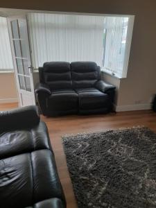 sala de estar con sofá de cuero negro y alfombra en Entire Three Bedroom House in Birmingham, en Birmingham