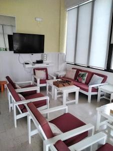 sala de estar con muebles de color rojo y blanco y TV de pantalla plana. en Esperides Hotel en Myrtos