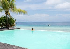 een vrouw in een zwembad die naar de oceaan kijkt bij My Blue Hotel Zanzibar in Nungwi