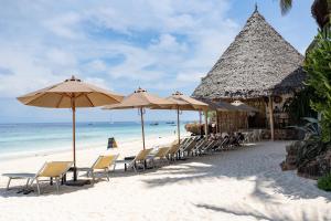 een strand met stoelen en parasols en de oceaan bij My Blue Hotel Zanzibar in Nungwi
