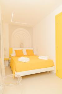 ein weißes Zimmer mit einem Bett mit einer orangefarbenen Decke in der Unterkunft La Chicca Apartments Castellammare Di Stabia in Castellammare di Stabia
