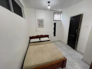 um pequeno quarto com uma cama no canto em Confortable 2 bedrooms - Center of Osu noble house em Acra