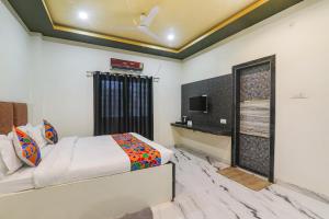 1 dormitorio con 1 cama y TV en la pared en FabHotel Saalt Bandhan Resort en Muzaffarpur