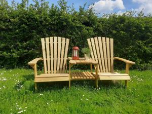 two chairs and a table in the grass with a tea kettle at Ferienhaus Deine Zeit mit SAUNA und WALLBOX in Nettersheim