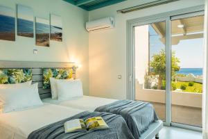 two beds in a bedroom with a view of the ocean at Paradisos in Frangokastello