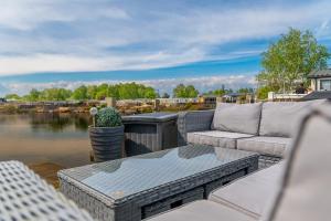 a patio with a couch and a table and water at Lake View with Private Hot Tub at Tattershall Lakes in Tattershall
