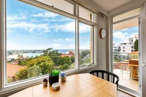 ein Esszimmer mit einem Tisch und einem großen Fenster in der Unterkunft Endless Views by Sydney Dreams with Parking in Sydney