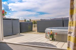a hot tub and a bottle of wine on a deck at Lake View with Private Hot Tub at Tattershall Lakes in Tattershall