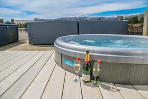 two bottles and two glasses of wine next to a hot tub at Lake View with Private Hot Tub at Tattershall Lakes in Tattershall