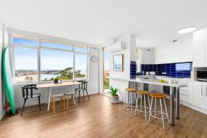 eine Küche mit weißen Schränken und einem Tisch mit Stühlen in der Unterkunft Endless Views by Sydney Dreams with Parking in Sydney