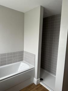 uma banheira branca na casa de banho com azulejos cinzentos em Immaculate 4-Bed Cottage in Knaresborough em Knaresborough