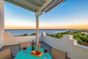 een tafel met wijnglazen en eten op een balkon met uitzicht op de oceaan bij Paradisos in Frangokastello