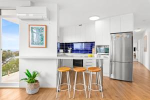 eine Küche mit zwei Hockern und einem Kühlschrank in der Unterkunft Endless Views by Sydney Dreams with Parking in Sydney