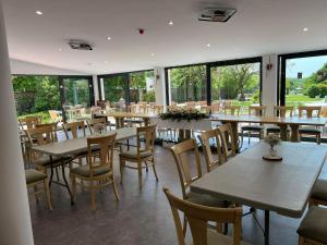 a restaurant with tables and chairs and large windows at Bakony Panzió in Tótvázsony