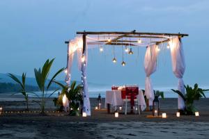 a dinner table under a tent on the beach at night at Kelapa Retreat & Spa in Pulukan