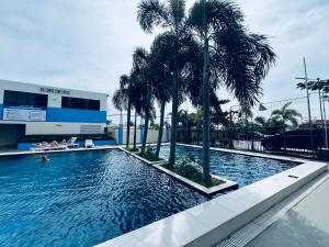 una piscina con palmeras frente a un edificio en Saekyung Condotel Near Airport en Lo-oc