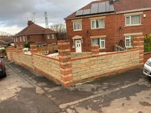 a brick retaining wall in front of a house at AICHELON Lodge in Wakefield