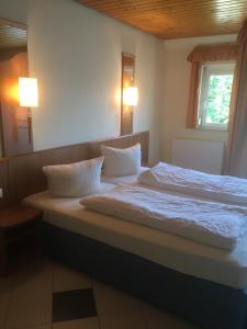 um quarto com uma cama com lençóis brancos e almofadas em Bakony Panzió em Tótvázsony